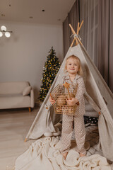 An attractive blonde girl in pajamas  is having fun in a wigwam on the background of a Christmas tree  © Татьяна Добрикова