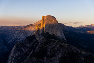 Fototapeta premium Experience the breathtaking beauty of Yosemite National Park at sunset behind Half Dome, where golden hues illuminate natures masterpiece, creating an unforgettable sense of tranquility and wonder