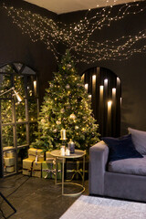 Christmas interior with a beautiful Christmas tree, sofa, light bulbs and dark background.