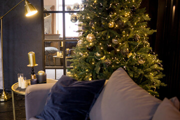 Christmas interior with a beautiful Christmas tree, sofa, light bulbs and dark background.