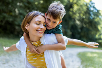 Young beautiful mother playing with her son piggy back.