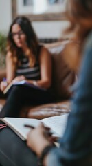 Fototapeta premium Two women share ideas and take notes in a warm, inviting living room during a casual meeting