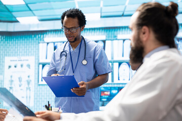 Expert medic discussing hospital records with specialists team in a meeting, medical staff coordinating for a new treatment plan. Staff at a private clinic analyzing exam test results.