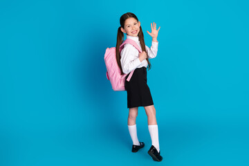 Full size photo of cute small schoolkid arm wave hi wear uniform isolated on blue color background
