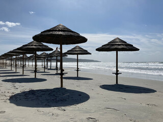 Sun parasol umbrellas on the beach in Porto Pino, Sardinia. Deserted empty beach with no people on a sunny day. Sun protection concept