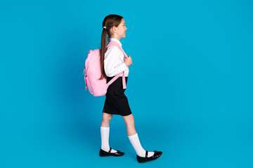Full size profile photo of cute small schoolkid walk empty space wear uniform isolated on blue...