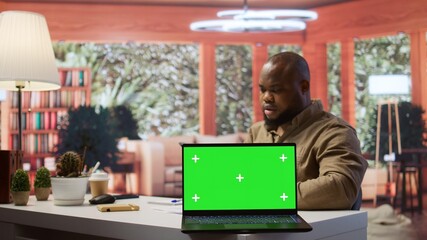 Young entrepreneur reviewing budget balance reports at his home desk, using mockup copy space...