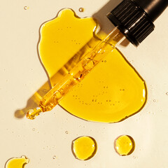 yellow oil pouring out of a pipette, drops of oil