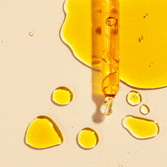 yellow oil pouring out of a pipette, drops of oil