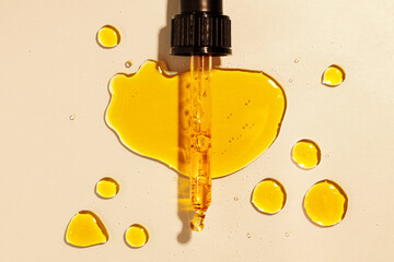 yellow oil pouring out of a pipette, drops of oil