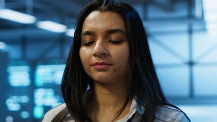 Engineer in high tech data center managing and maintaining databases, ensuring data integrity, security and availability. Indian woman updating server room supercomputers systems, camera A