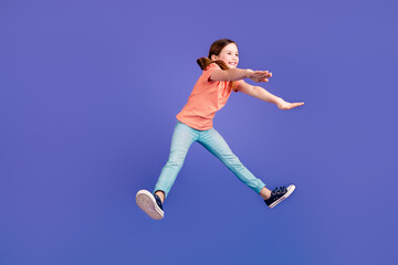 Full size photo of pretty little girl jumping pushing invisible things wear trendy red outfit isolated on purple color background