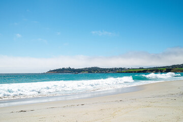 View of cliff and foamy waves in the distance from the beach
