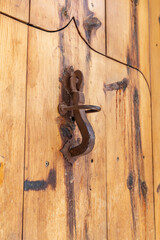 A rusted knocker on a wooden door.