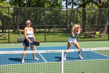 Obraz premium Female pickleball player returns ball while her partner watches.