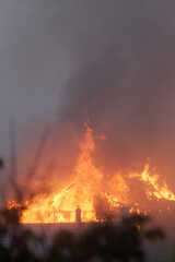 Home is engulfed in flames, creating a raging inferno with thick smoke, causing destruction and requiring immediate rescue efforts