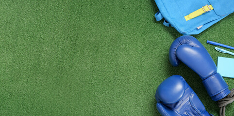 Backpack with boxing gloves, skipping rope and stationery on color background