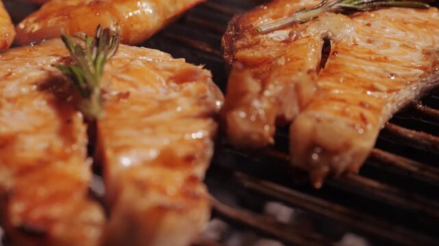 Chef cooking red salmon fish steaks with oil and spices on grill close-up. Prawns on fire throwing them on pan. Making Dorado fishes on frying grill. Restaurant Food concept