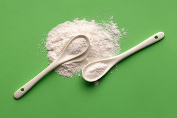 Baking soda in two spoons - Healthy food. Green background