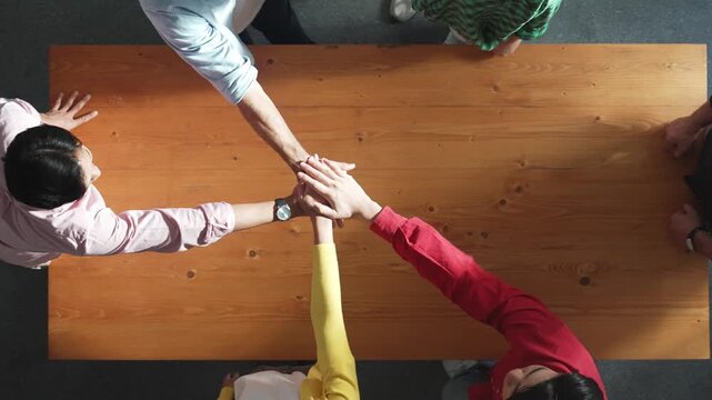 Close up of happy start up business people hand putting hands together at meeting and clapping hand to celebrate collaboration and increasing sales or encourage teamwork and togetherness. Convocation.