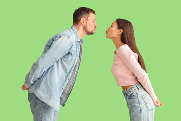Young couple kissing on green background