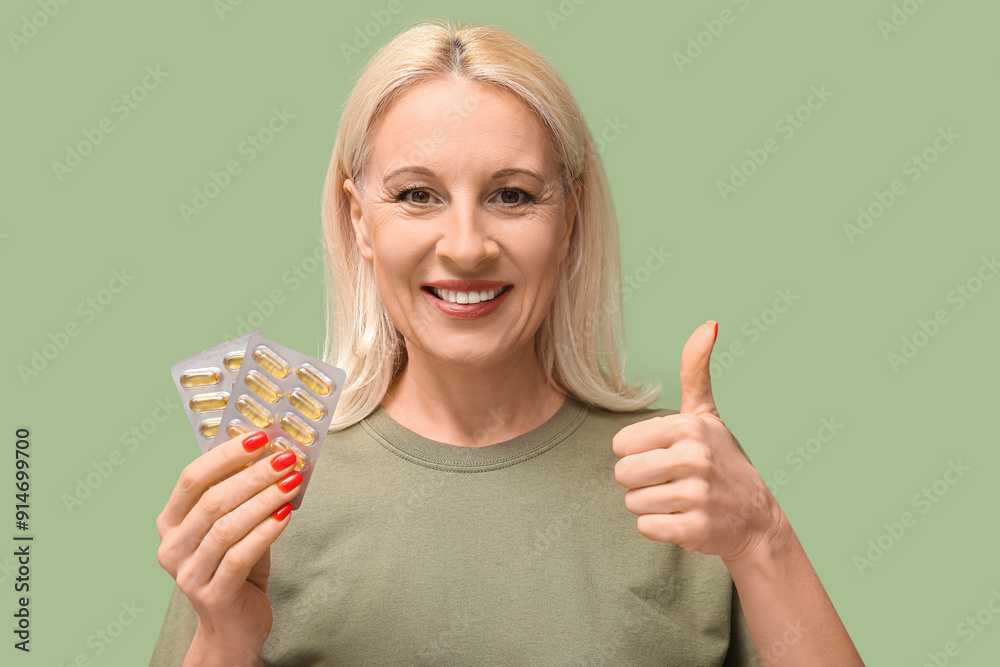 Sticker Mature woman with fish oil pills showing thumb-up gesture on green background