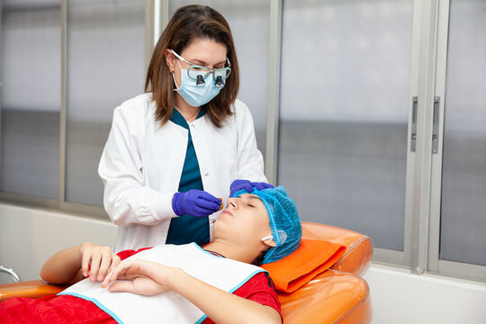 Skin lesion removal procedure. Dermatologist carrying out a removal of benign skin lesion on the face of a young male patient.