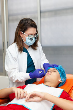 Skin lesion removal procedure. Dermatologist carrying out a removal of benign skin lesion on the face of a young male patient.