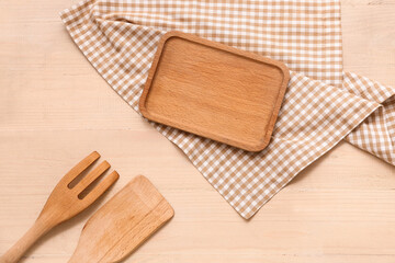 Napkin with fork, spatula and board on wooden background