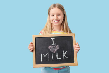 Little girl holding blackboard with text I LOVE MILK on blue background