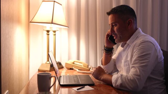 Hombre hablando por celular y trabajando en su computadora preocupado