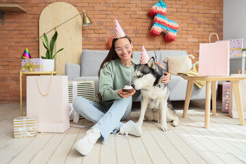Young woman and cute husky dog with party hats and cake at home. Birthday celebration © Pixel-Shot