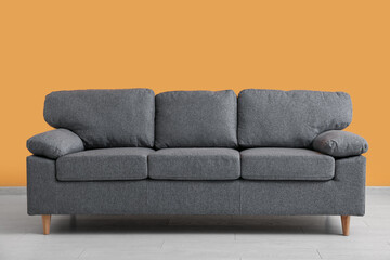 Cozy sofa near orange wall in stylish living room