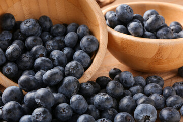 Bowls with sweet fresh blueberries on wooden background, closeup