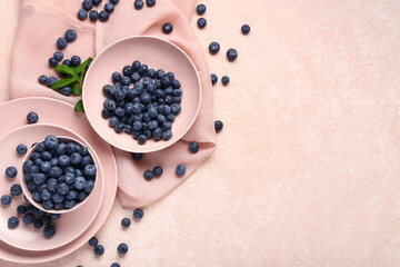 Bowl and plate with sweet fresh blueberries on pink background