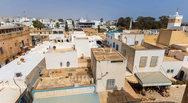 Aerial view of rooftops and streets in densely packed residential area of Hammamet Medina bathed in hot Tunisian sunny.