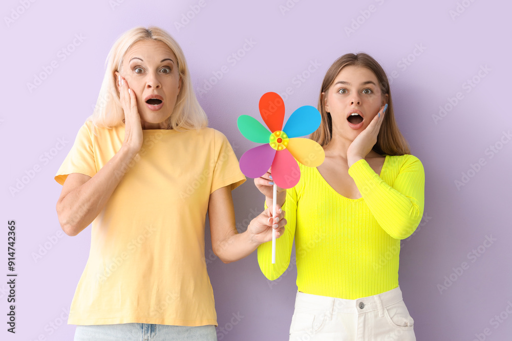 Canvas Prints shocked mature woman and her daughter with toy windmill on lilac background