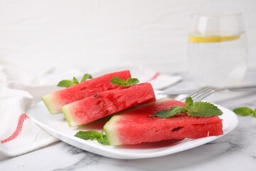Fresh watermelon slices with mint leaves on white marble table, closeup
