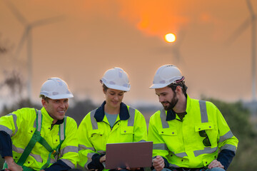 Fototapeta premium Team Engineers men and woman checking and inspecting on construction with sunset sky. people operation. Wind turbine for electrical of clean energy and environment. Industrial of sustainable.