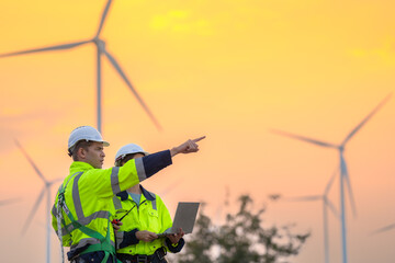 Engineers man and woman inspecting construction of WIND TURBINE FARM. WIND TURBINE with an energy...