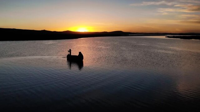 Typical man from Puno Peru sailing on Titicaca Lake with traditional boat at sunset