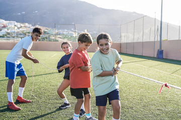 Sport, Group of children playing rope pulling game at school soccer field. Children having fun...