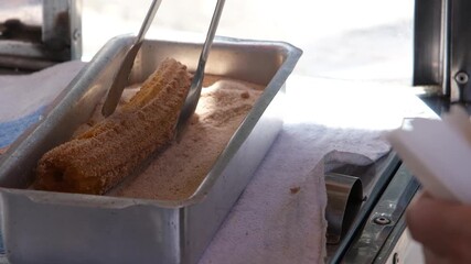 Woman passing fried churros through sugar and cinnamon_7.