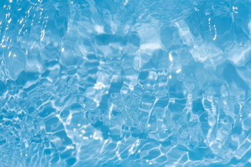 Blue water with ripples on the surface. Defocus blurred transparent blue colored clear calm water surface texture with splashes and bubbles. Water waves with shining pattern texture background.