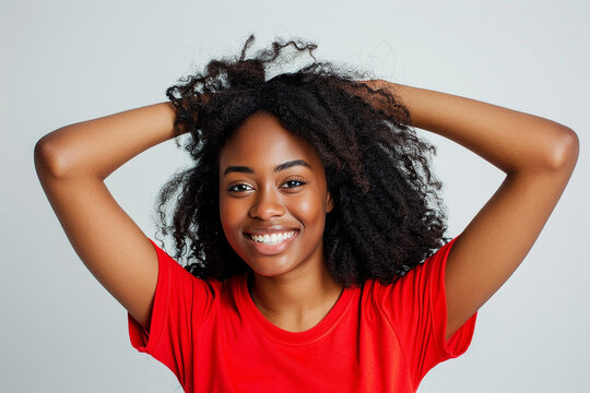 Beautiful woman with hair, happy and smiling while touching her hair against a grey background. posing for a beauty concept