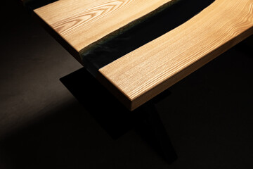 Expensive vintage furniture. The table is covered with epoxy resin and varnished. Luxury quality wood processing. Wooden table on a dark background. Black river made of epoxy resin.