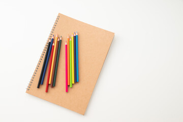 Obraz premium Colored pencils with notebook on white background. School and office supplies image. 
