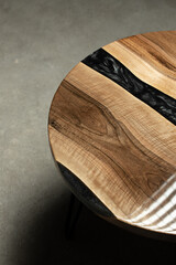 Expensive vintage furniture. The table is covered with epoxy resin and varnished. Luxury quality wood processing. Wooden table on a dark background. A black epoxy river in a round tree slab.	