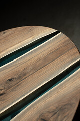 Expensive vintage furniture. The table is covered with epoxy resin and varnished. Luxury quality wood processing. Wooden table on a dark background. A blue epoxy river in a round tree slab.