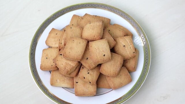 Delicious black cumin biscuits on a white plate with wooden background.